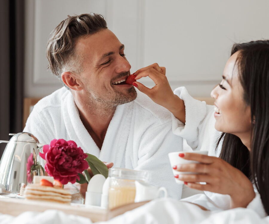 Paar im Bett liegend mit Frühstück
