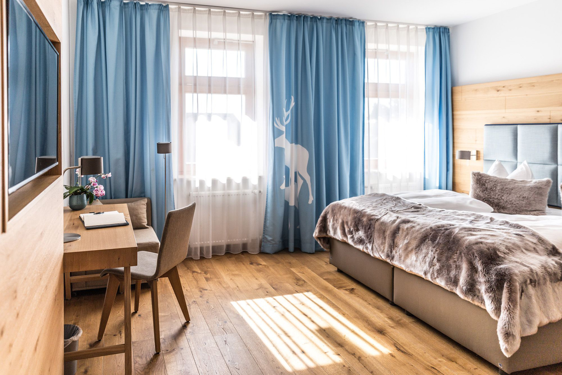 Zimmeransicht mit Schreibtisch und Fensterfront im Das Aunhamer